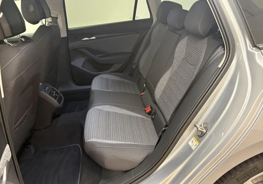 Vue intérieure côté droit des sièges arrière gris tissu et cuir d'une Skoda Superb Combi 2025 gris argent avec aérateurs centraux.