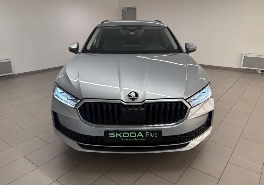 Vue avant frontale du Skoda Superb Combi gris argent avec phares LED allumés et calandre noire brillante.
