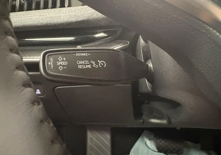 Gros plan sur la commande de régulateur de vitesse au volant d'un Skoda Superb Combi gris argent.