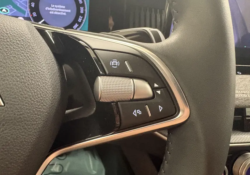 Gros plan sur les commandes au volant du Skoda Superb Combi 2025, finition noire avec molette métallique texturée.