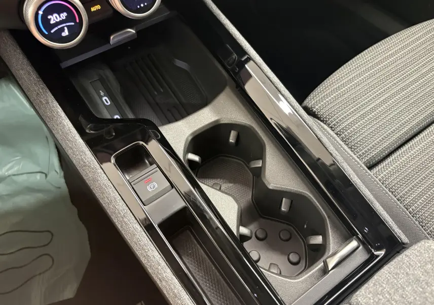 Gros plan sur la console centrale intérieure de la Skoda Superb Combi 2025, avec porte-gobelets et bouton frein à main électrique.