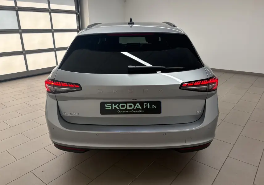 Vue arrière d'une Skoda Superb Combi gris argent avec feux LED allumés dans un garage lumineux.