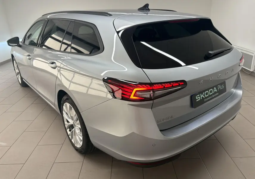 Vue 3/4 arrière droite d'une Skoda Superb Combi gris argent avec feux LED et jantes alliage 18 pouces.