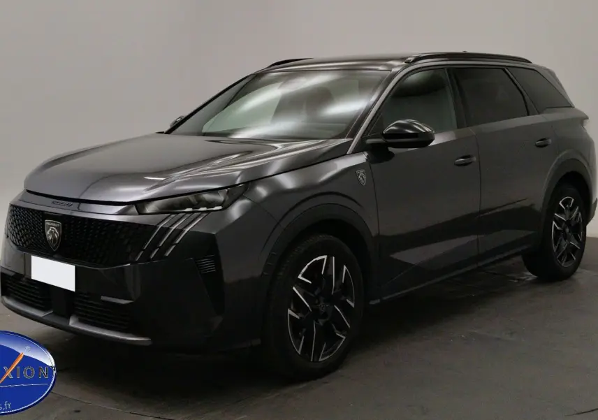 Peugeot 5008 gris titane en 3/4 avant droit, avec jantes noires et phares LED allumés, en showroom.