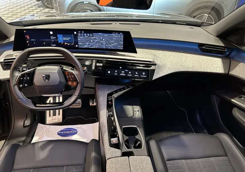 Vue intérieure avant du Peugeot 5008 III Hybrid gris Titane, avec tableau de bord numérique et volant multifonction.