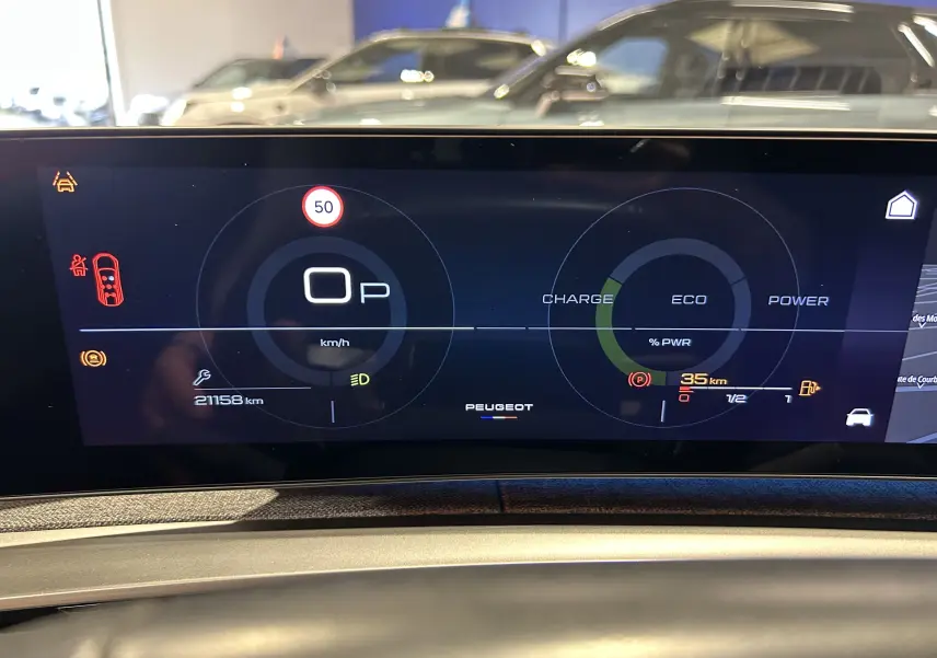 Tableau de bord numérique du Peugeot 5008 hybride 2025 affichant vitesse, autonomie et indicateurs de charge en gros plan.