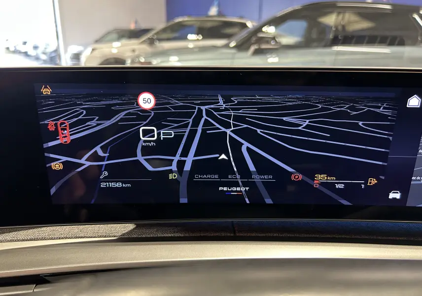 Écran numérique de tableau de bord du Peugeot 5008 III Hybrid 145, affichant la navigation et les informations de conduite.