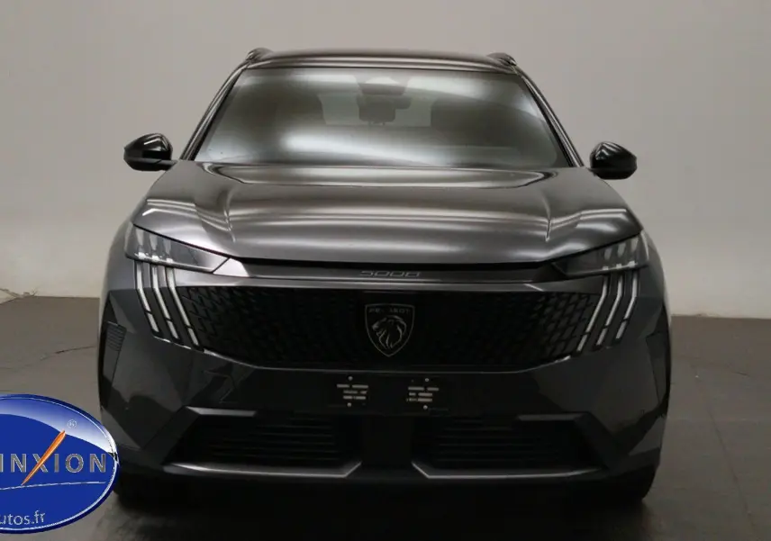 Vue avant rapprochée du Peugeot 5008 gris titane avec feux LED distinctifs et calandre noire brillante.