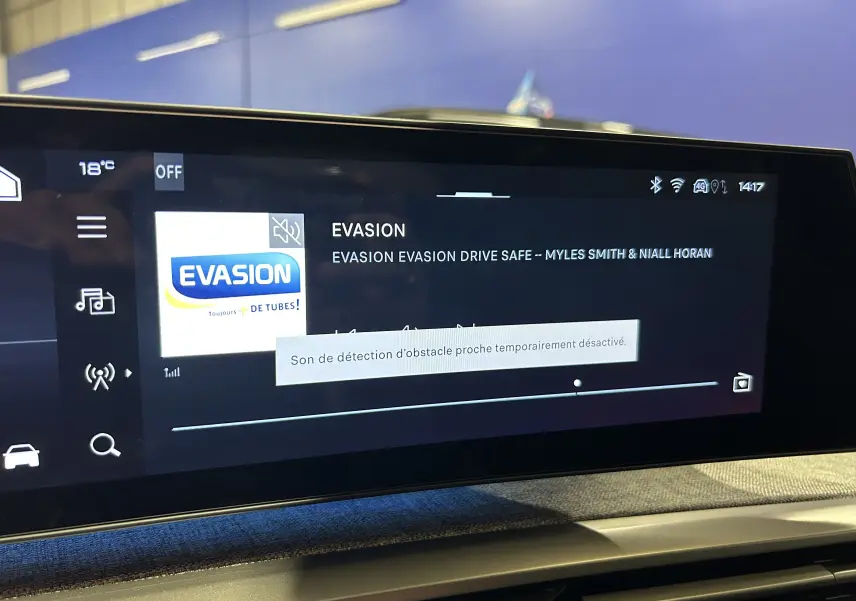 Écran tactile central du tableau de bord du Peugeot 5008 III Hybrid 145, affichant une radio et une notification sonore.
