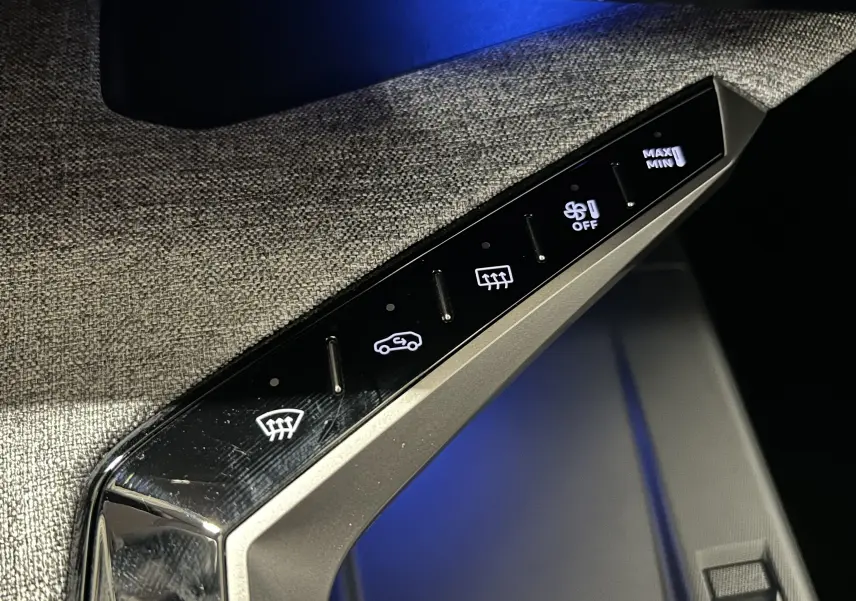 Gros plan sur les commandes de climatisation avec éclairage blanc, sur la console intérieure du Peugeot 5008 gris Titane.