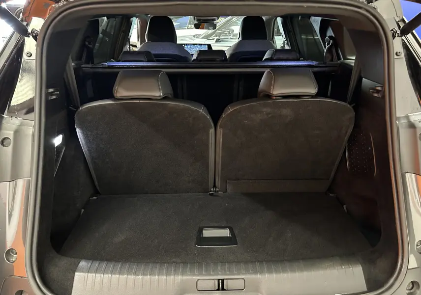 Coffre ouvert vu de l'arrière d'un Peugeot 5008 gris titane, montrant la troisième rangée de sièges relevée.