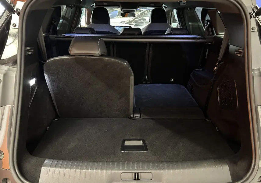 Coffre ouvert du Peugeot 5008 gris titane, vue arrière montrant la banquette arrière partiellement rabattue.
