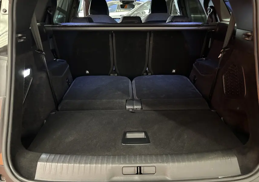 Coffre ouvert vu de l'arrière du Peugeot 5008 gris titane, sièges arrière rabattus pour un grand espace de chargement.