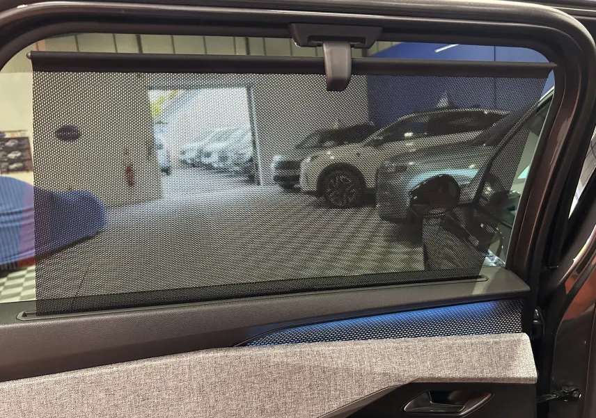 Vue intérieure du côté gauche de la porte arrière du Peugeot 5008 gris Titane avec pare-soleil en filet déployé.