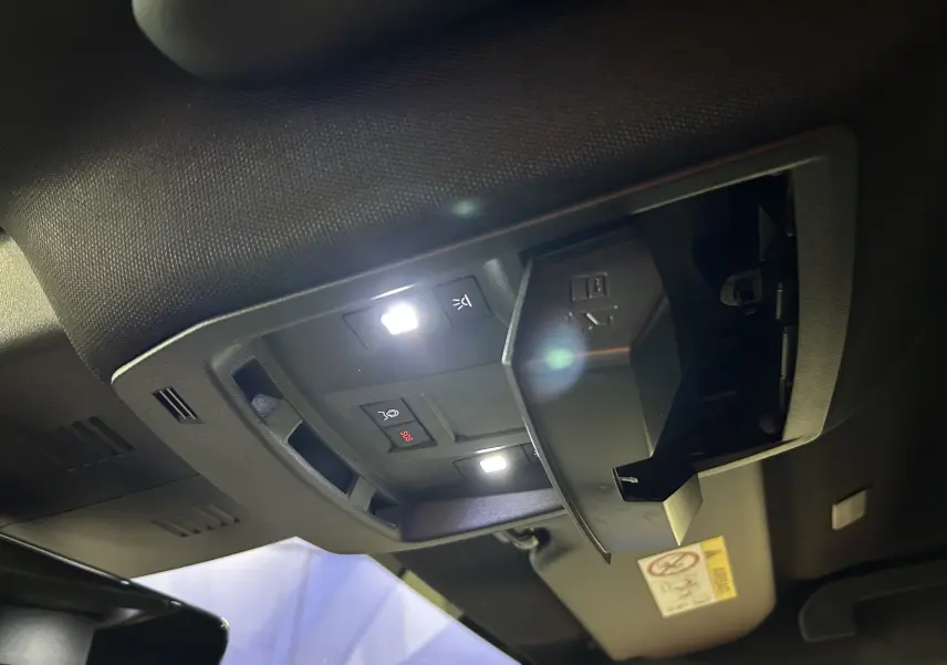 Détail du plafonnier intérieur avec éclairages LED et compartiment lunettes ouvert dans un Peugeot 5008 gris Titane.