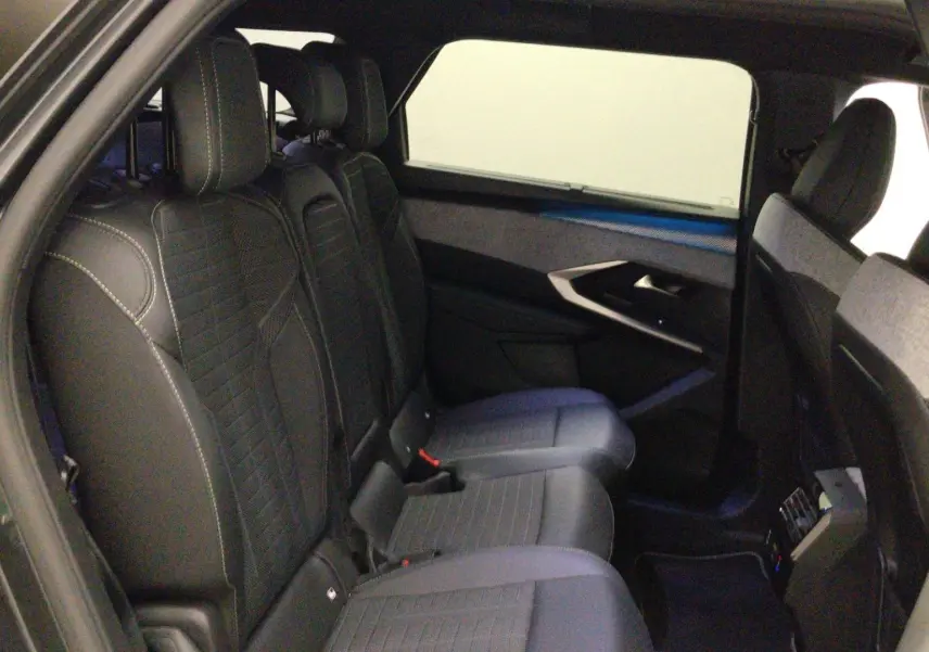 Vue intérieure côté conducteur du Peugeot 5008 III Hybrid 145 e-DCS6 GT, sièges noirs avec logo Peugeot brodé sur les appuie-têtes.