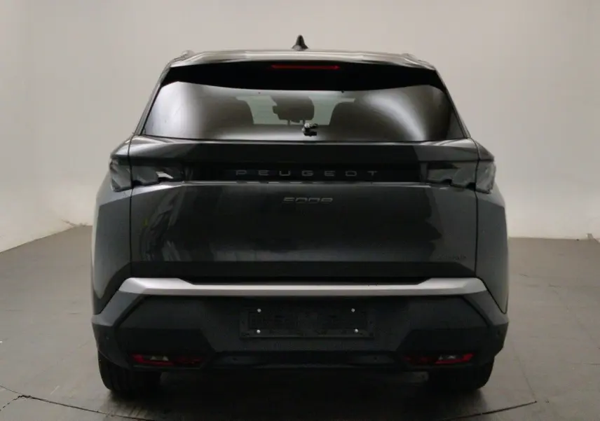 Peugeot 5008 III Hybrid gris titane en 3/4 avant droit, avec phares LED allumés et jantes noires biton.