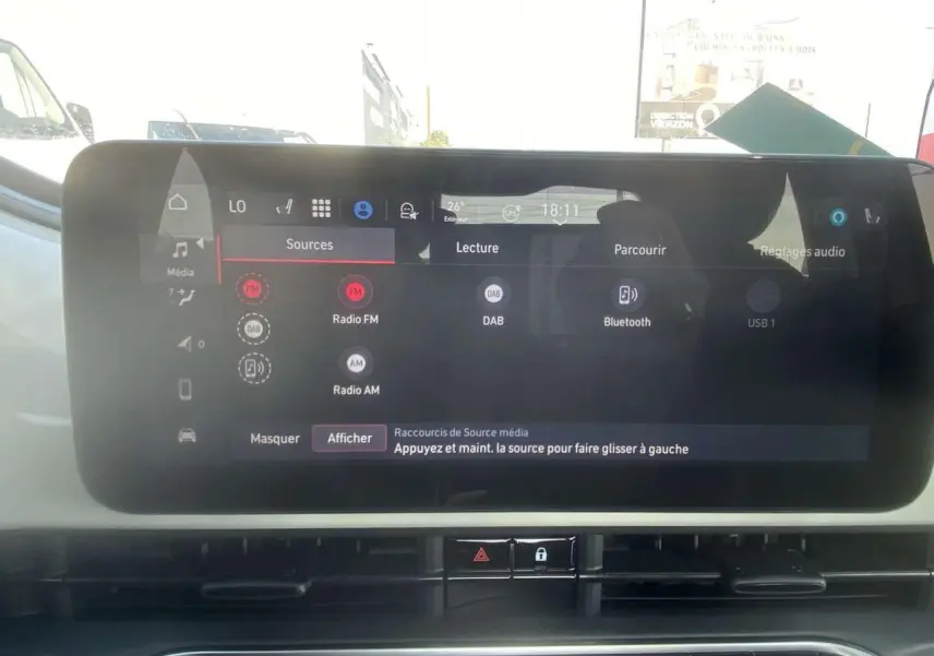 Écran tactile central de la Fiat 500 Électrique 2022, affichant les options audio avec tableau de bord blanc en arrière-plan.