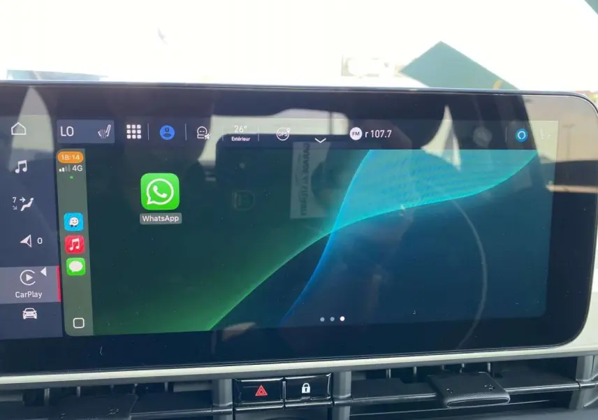 Écran tactile central de la Fiat 500 Electrique blanche 2022 affichant l'interface Apple CarPlay avec WhatsApp ouverte.