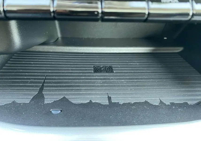 Gros plan sur le chargeur à induction noir avec motif de skyline, intérieur de la Fiat 500 électrique blanche 2022.