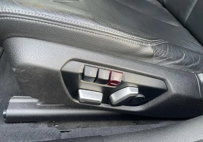 Détail des commandes de réglage électrique du siège conducteur en cuir noir d'une BMW Série 3 F30 330i xDrive.