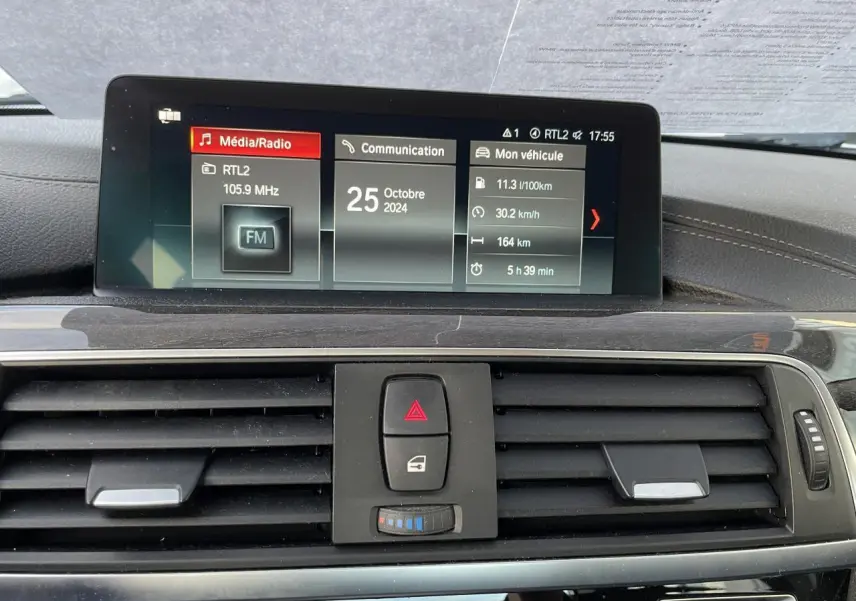 Écran multimédia et commandes centrales du tableau de bord en bois foncé d'une BMW Série 3 F30 gris clair de 2018.