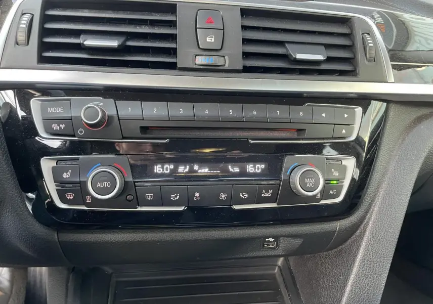 Console centrale noire brillante de la BMW Série 3 F30 330i xDrive 2018 avec commandes climatisation automatique et radio.