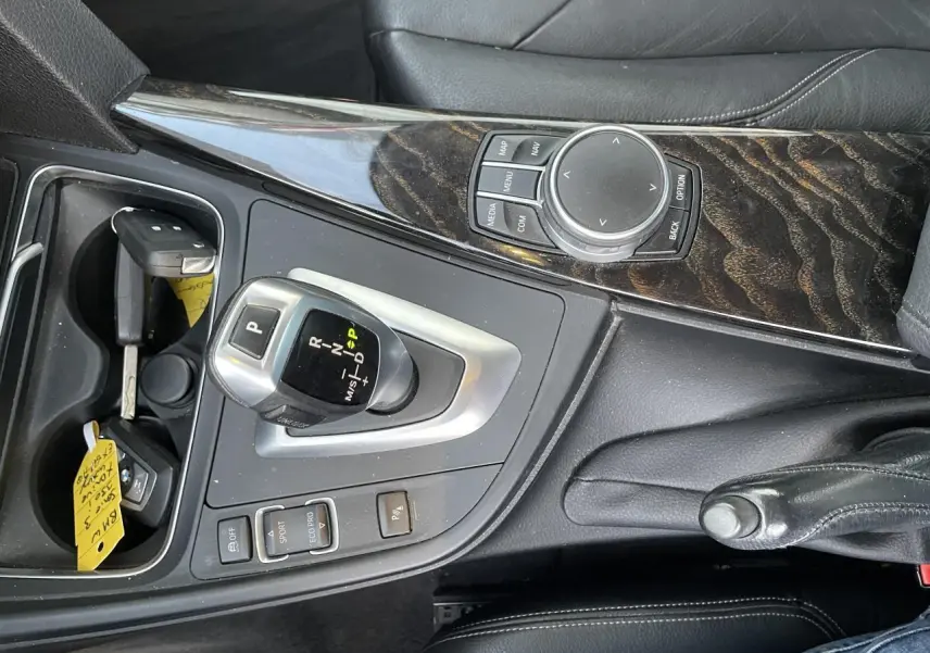 Vue rapprochée de la console centrale en bois précieux et cuir noir avec levier de vitesse automatique d'une BMW Série 3 F30.