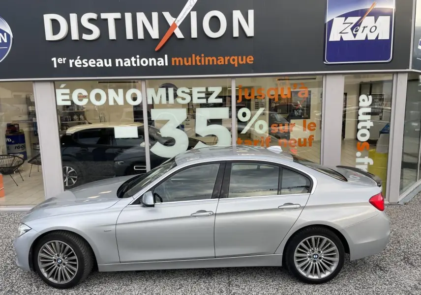 BMW Série 3 F30 330i xDrive Luxury gris clair vue profil côté gauche devant une vitrine avec enseigne Distinxion