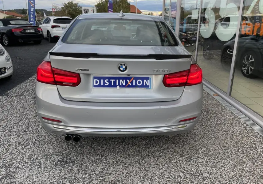 Vue arrière d'une BMW Série 3 F30 gris clair 330i xDrive avec double sortie d'échappement et badge distinctif.