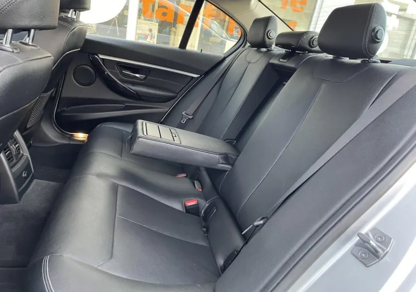 Vue intérieure côté droit de la banquette arrière en cuir noir avec accoudoir central relevé d'une BMW Série 3 F30 gris clair.