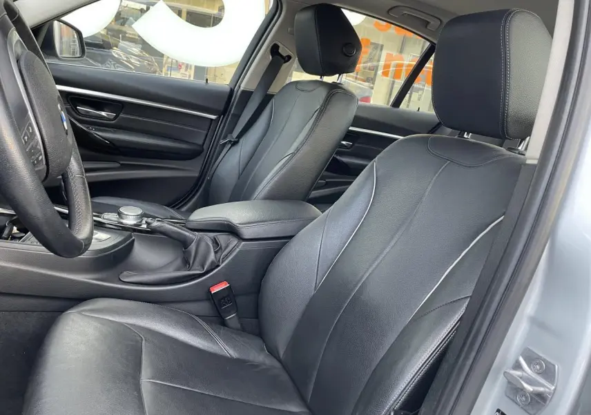 Intérieur avant droit de BMW Série 3 F30 gris clair avec sièges cuir noirs et accoudoir central coulissant.