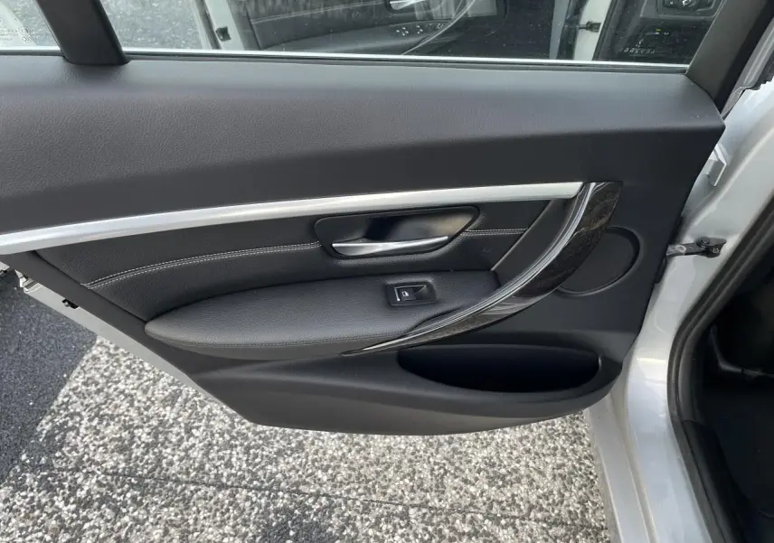 Porte arrière droite ouverte d'une BMW Série 3 F30 gris clair, avec garniture noire et insert décoratif brillant.