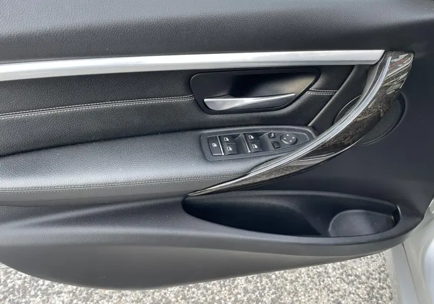 Poignée intérieure côté gauche de porte BMW Série 3 F30 gris clair avec garniture cuir noire et insert chromé brillant.