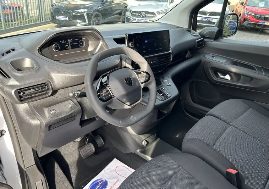 Intérieur du Peugeot Partner Fourgon 2025 vu côté conducteur, tableau de bord moderne avec écran tactile et volant compact noir.