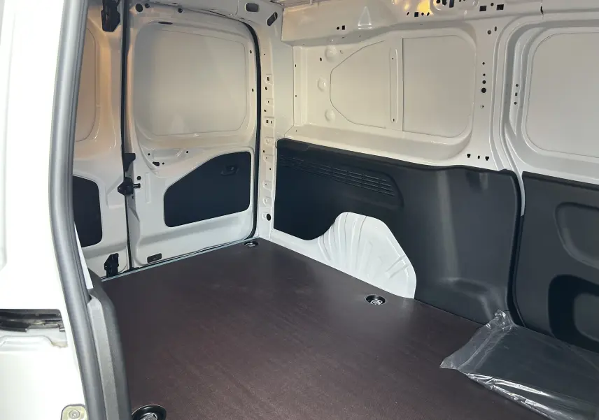 Intérieur du fourgon blanc Peugeot Partner 2025, vue du plancher bois et parois arrière côté gauche.