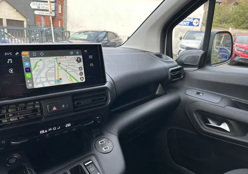 Vue intérieure côté passager du tableau de bord noir du Peugeot Partner Fourgon 2025 avec écran tactile et commandes climatisation.
