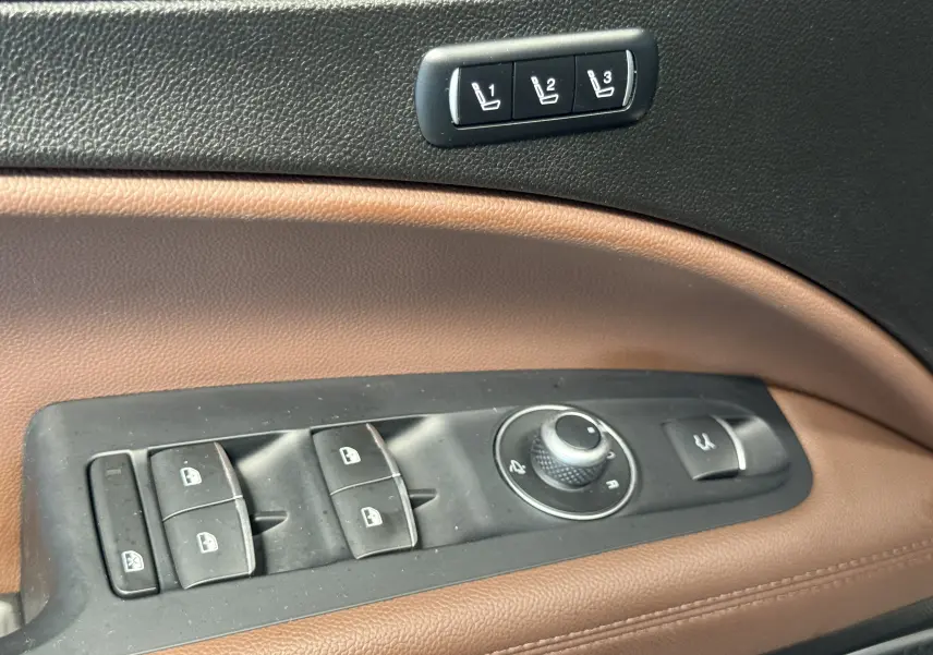 Gros plan sur les commandes de porte en cuir marron et noir de l'Alfa Romeo Stelvio 2017, incluant réglages des vitres et mémoires sièges.