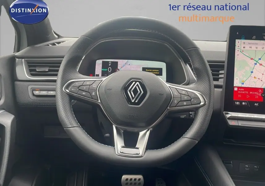 Vue rapprochée du volant noir perforé et du tableau de bord numérique du Renault Captur E-Tech hybride 2025.