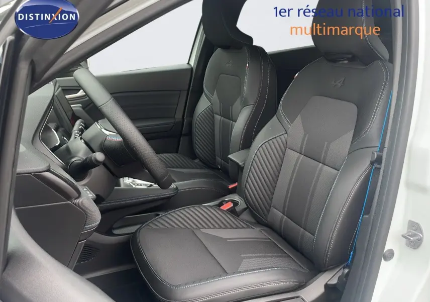 Intérieur avant du Renault Captur E-Tech hybride 2025 avec sièges noirs en cuir et surpiqûres bleues, porte blanche ouverte.