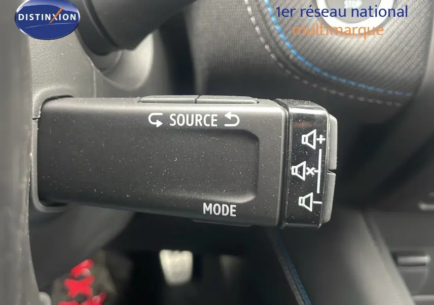 Commande au volant avec boutons source et mode, volant noir avec surpiqûres bleues dans Renault Captur E-Tech hybride 2025