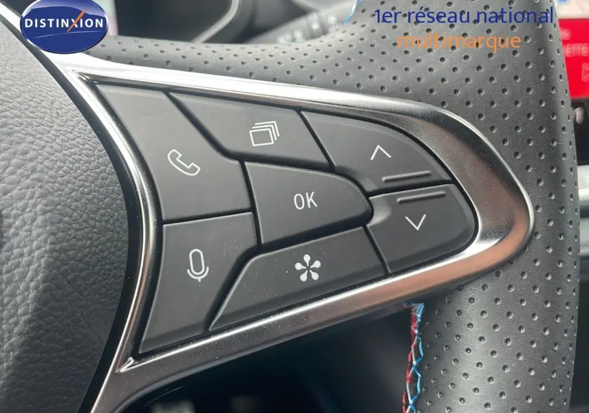 Gros plan sur les commandes multifonctions du volant en cuir perforé du Renault Captur E-Tech blanc nacré toit noir.