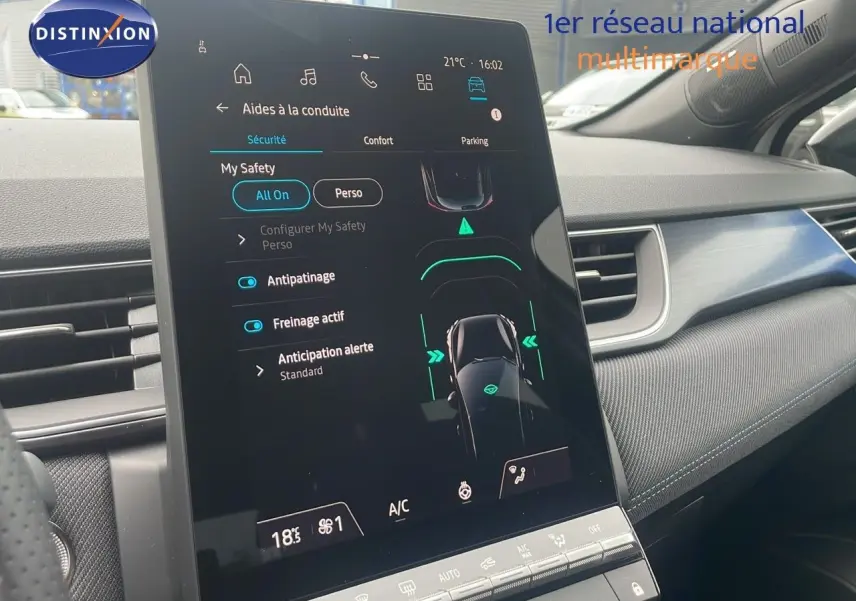 Écran tactile central affichant les aides à la conduite dans l’habitacle d’un Renault Captur blanc nacré toit noir, vue de côté droit.