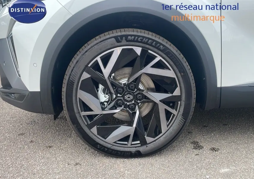 Gros plan sur la roue avant gauche du Renault Captur blanc nacré avec jante noire et argentée au design géométrique.