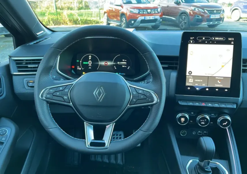 Vue intérieure centrée sur le volant cuir multifonctions et l'écran tactile du tableau de bord de la Renault Clio gris schiste.