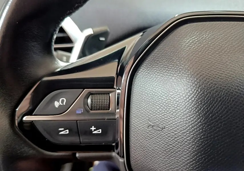 Gros plan sur les commandes gauche du volant cuir du Peugeot 3008 blanc hybride rechargeable, finition Allure 2020.