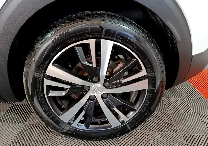 Gros plan sur la jante alliage bicolore noire et argentée du Peugeot 3008 blanc, roue avant droite visible.