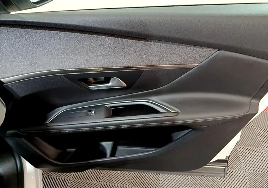 Vue intérieure côté gauche de la porte avant d'une Peugeot 3008 blanche avec garniture noire et poignée argentée.