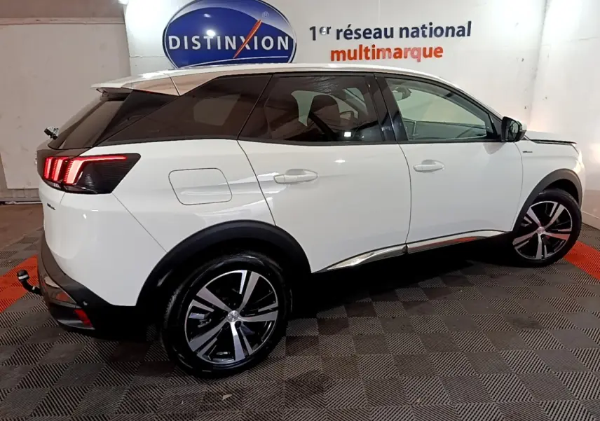 Peugeot 3008 hybride rechargeable blanc vue côté droit en intérieur avec feux arrière LED allumés et jantes alliage.