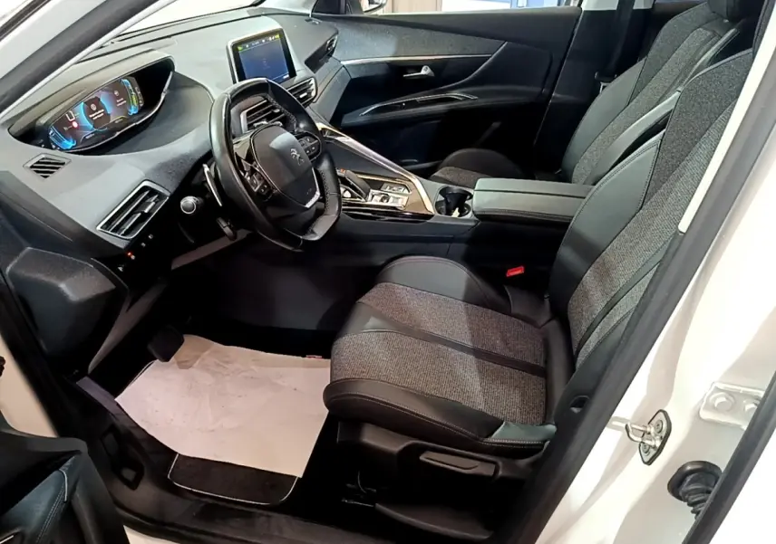 Vue intérieure côté conducteur du Peugeot 3008 blanc 2020, avec tableau de bord digital et sièges tissu-cuir gris.